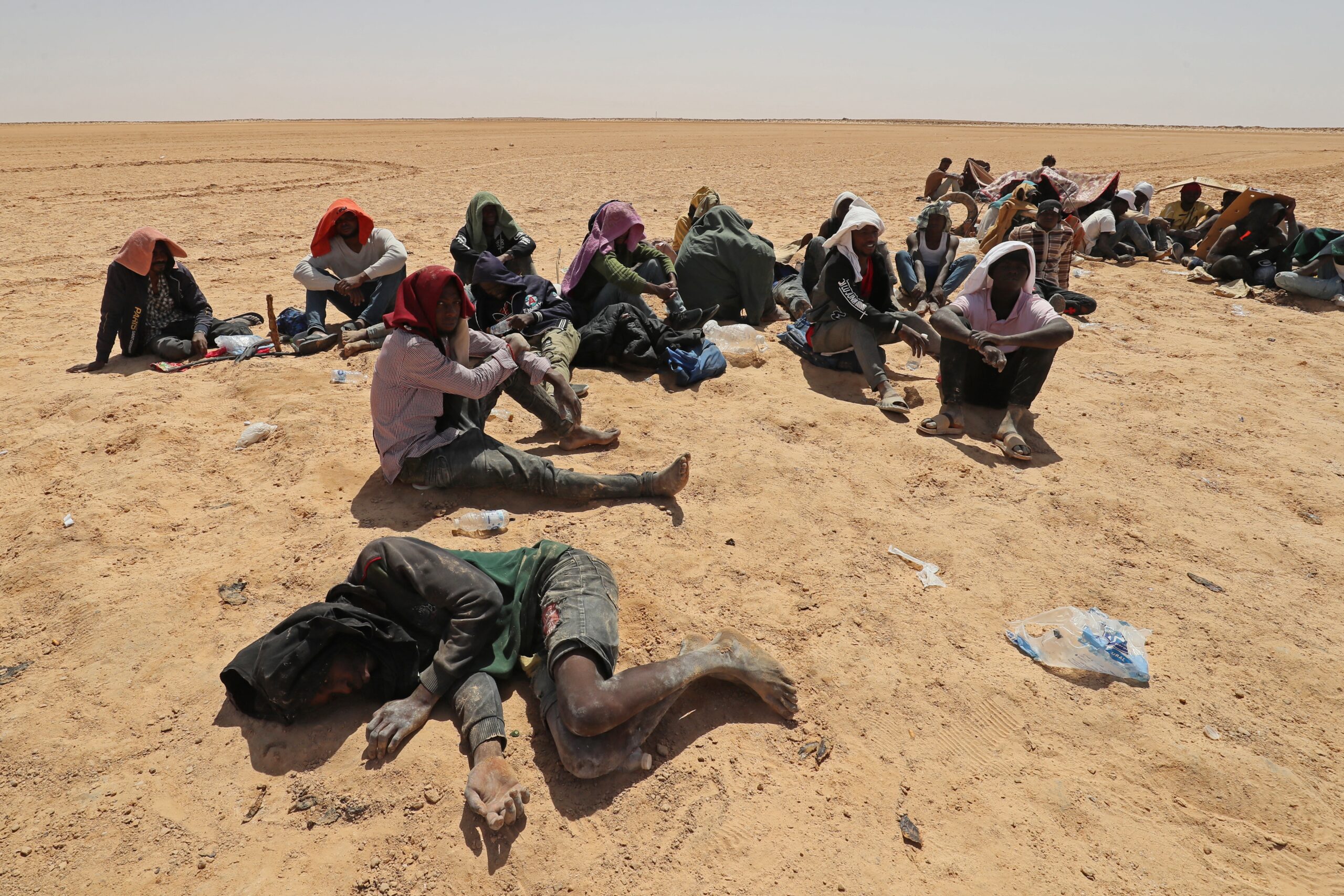 Migranten uit Afrikaanse landen ten zuiden van de Sahara die beweren door de Tunesische autoriteiten in de woestijn te zijn achtergelaten zonder water of onderdak, zitten op 16 juli 2023 in een onbewoond gebied in de buurt van de Libische grensstad Al-Assah. Honderden migranten uit Afrikaanse landen ten zuiden van de Sahara werden gedwongen naar woestijngebieden en vijandige gebieden grenzend aan Libië en Algerije gebracht na onrust begin juli in Sfax, de op een na grootste stad van Tunesië. Migranten uit Afrikaanse landen ten zuiden van de Sahara die beweren door de Tunesische autoriteiten in de woestijn te zijn achtergelaten zonder water of onderdak, zitten op 16 juli 2023 in een onbewoond gebied in de buurt van de Libische grensstad Al-Assah. Honderden migranten uit Afrikaanse landen ten zuiden van de Sahara werden gedwongen naar woestijngebieden en vijandige gebieden grenzend aan Libië en Algerije gebracht na onrust begin juli in Sfax, de op een na grootste stad van Tunesië.