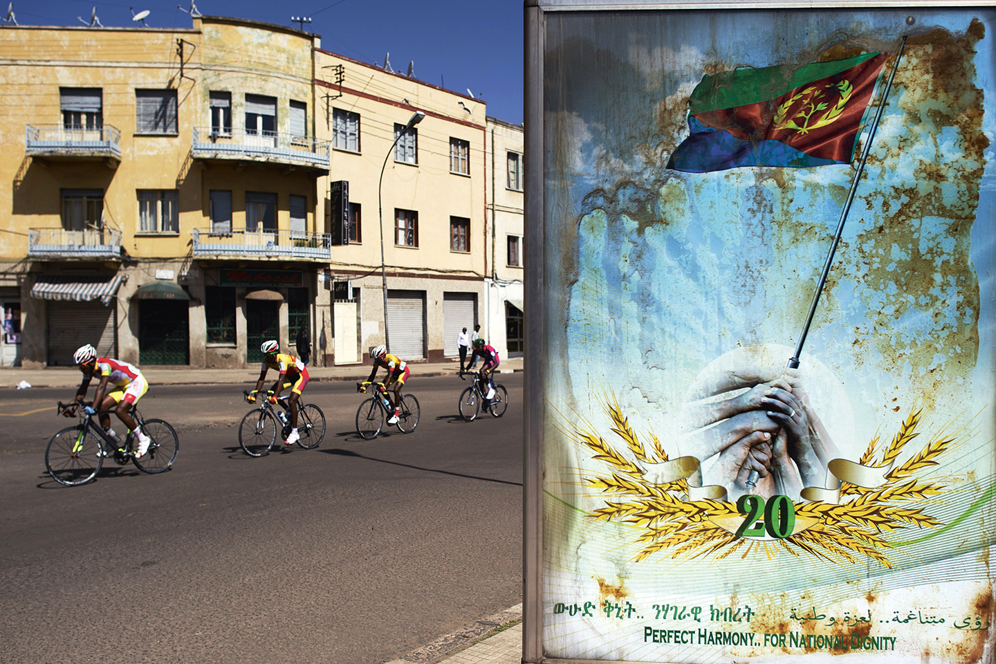 Wielrenners passeren een poster met de tekst ‘Perfecte Harmonie voor Nationale Waardigheid’ tijdens een straatrace in hoofdstad Asmara.
