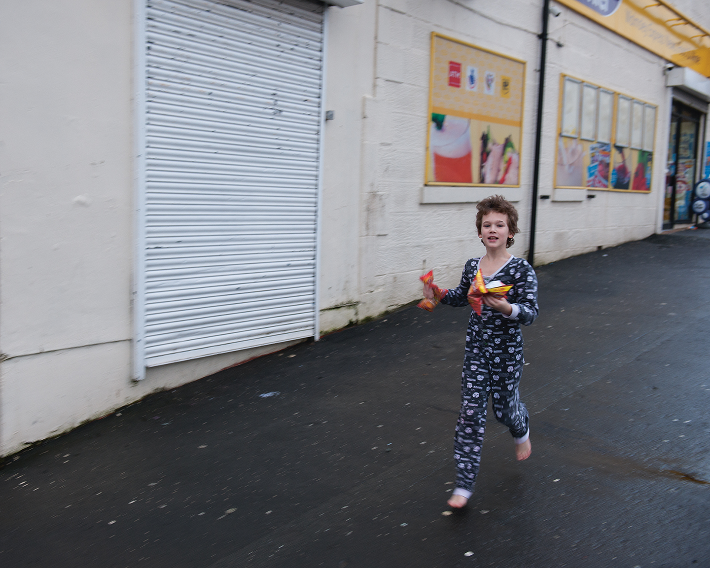 Elliot, een van de kinderen van Mark, rent op blote voeten over straat. (Uit de serie Thatcher's Children)