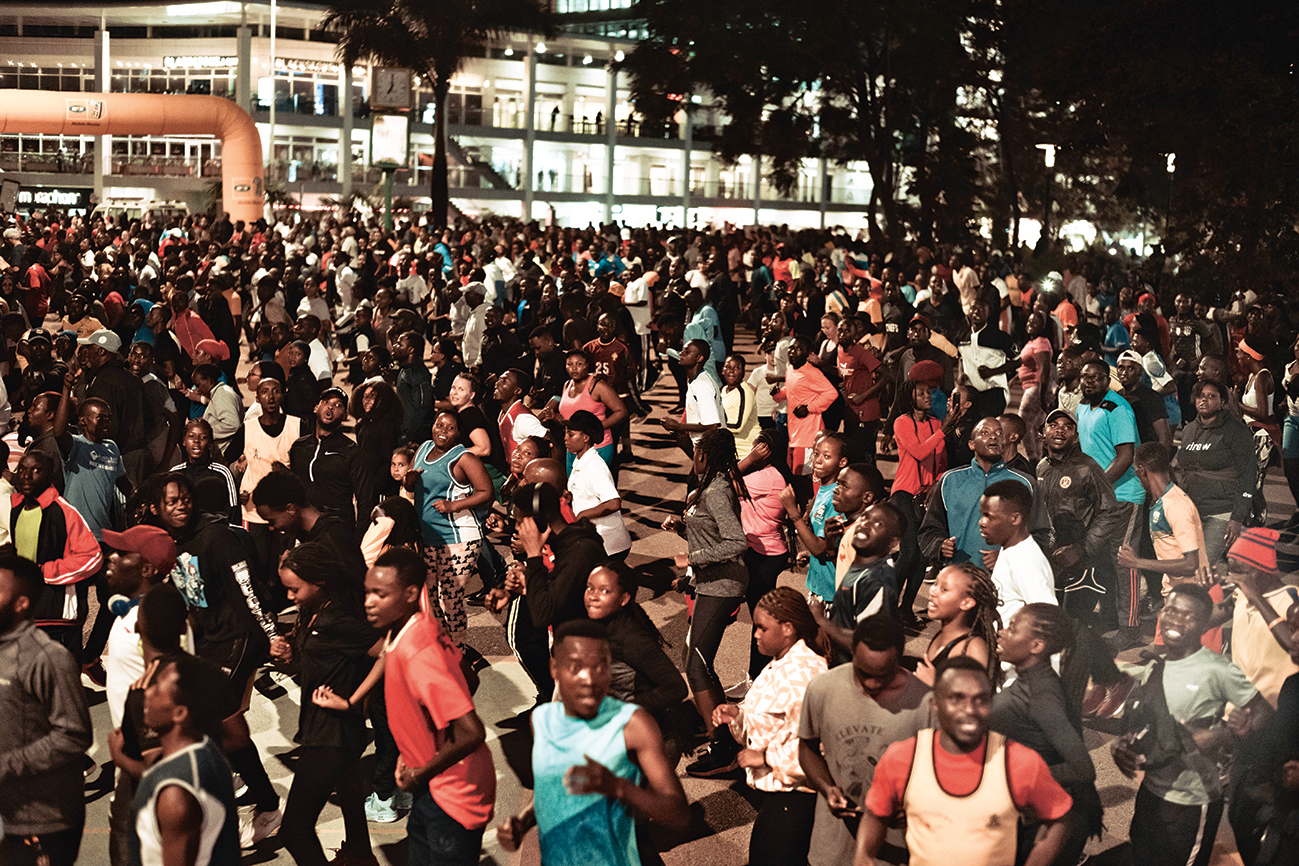 In de binnenstad van hoofdstad Kigali volgt een menigte de gezamenlijke warming-upsessie voor de Kigali Night Run, een hardloopevenement.