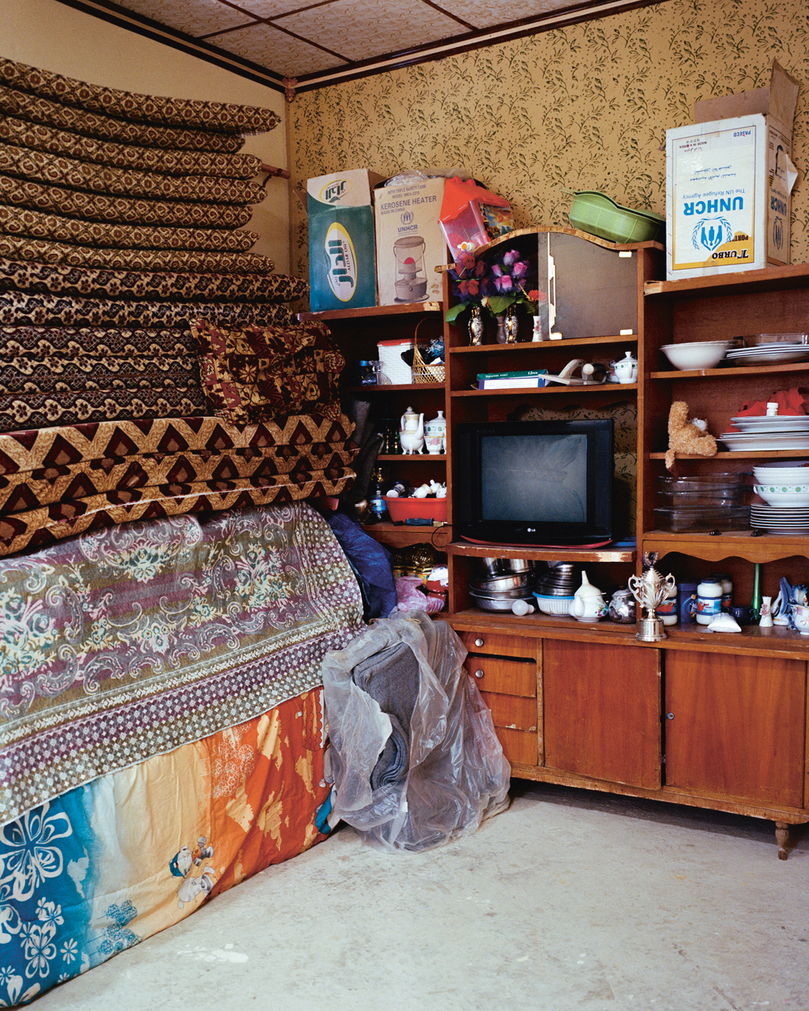 In een huis in Sherfedin liggen matrassen opgestapeld. Normaal gesproken kunnen hier ’s nachts familieleden en andere gasten op slapen. In de kast zie je een doos met het logo van UNHCR, de vluchtelingenorganisatie van de VN.