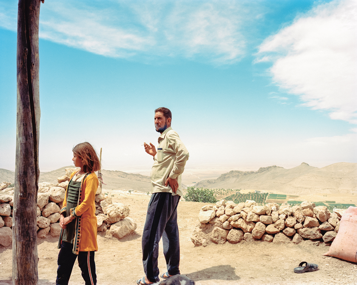 Barakat, een Jezidi, met een van zijn dochters voor hun huis, verafgelegen in de bergen.