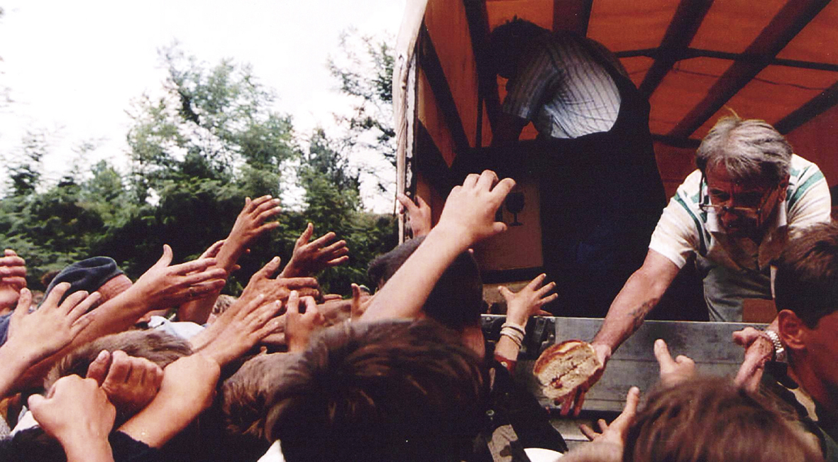 Een VN-medewerker deelt brood uit aan vluchtelingen uit Srebrenica (juli 1995)