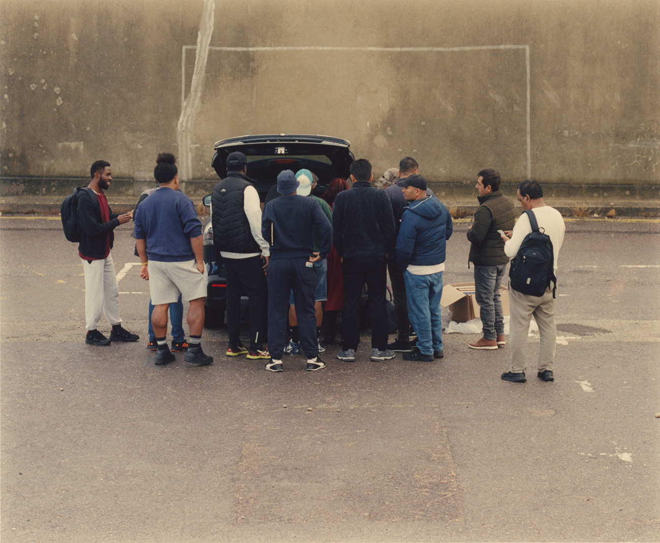 Kay en Gary, werkzaam voor een hulporganisatie, delen goederen uit aan asielzoekers uit de achterbak van hun auto.